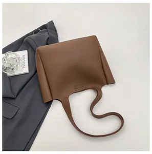 Detail of a brown faux leather tote bag showing smooth texture and trapezoidal structure
