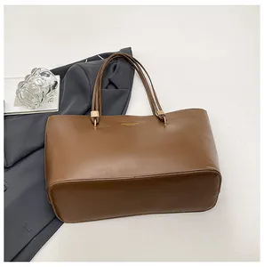 Detail shot of brown leather tote bag with gold lettering and wide bottom base