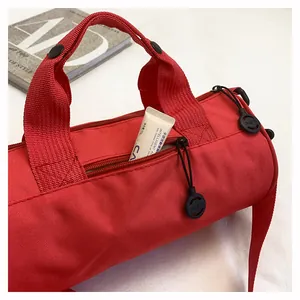 Close-up of durable red nylon cylinder bag featuring textured fabric and brand zipper detail