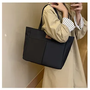 Détail du sac cabas noir avec empiècement en cuir marron sur tissu nylon