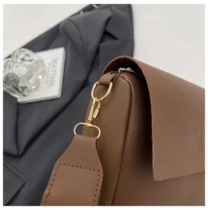 Detailed shot of dark brown leather crossbody bag featuring gold hardware and D-ring
