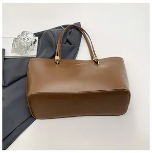 Detailed close-up of dark brown tote bag with multi-strand handles and gold metal rings
