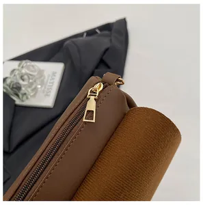 Close-up of golden zipper and textured leather stitching on a brown shoulder bag