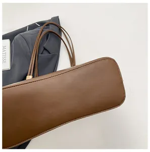 Detail shot of brown leather tote bag showing base stitching and gold metal hardware
