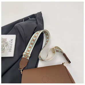 Detail of brown PU leather shoulder bag featuring a geometric ethnic style wide strap