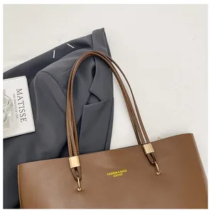 Detailed view of brown leather tote bag with gold buckles and fashion logo imprint