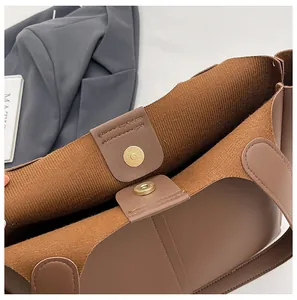 Detailed close-up of golden magnetic buckle closure and soft suede lining on tote bag