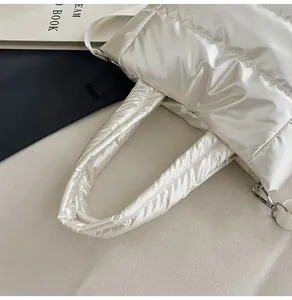 Détail du sac matelassé avec crochets métalliques et finition satinée blanc perle