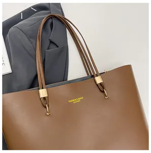 Detail of brown leather tote bag with gold metal buckles and fashion print text