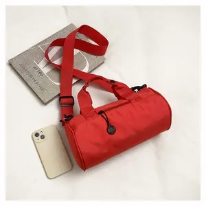 Top view of a red cylindrical mini travel bag next to a book and smartphone for size