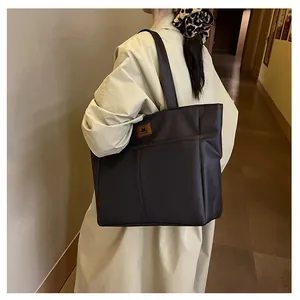 Grand sac fourre-tout marron foncé porté avec un trench beige pour un style minimaliste