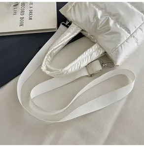 Gros plan du sac en nylon matelassé crème avec poignée rembourrée et détails argentés