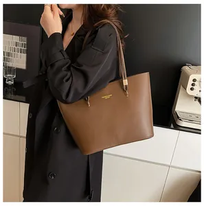 Brown leather tote bag featuring golden text and a spacious trapezoidal design