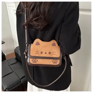 Detail view of a cute cartoon cat crossbody bag in soft brown faux suede on a model