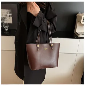 Detail of dark brown leather tote bag with gold metal hardware and fashion text engraving
