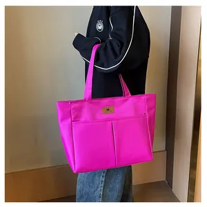 Détail du sac cabas en nylon magenta montrant les poches avant et la matière texturée