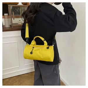 Close-up of bright yellow barrel travel bag with adjustable strap and top handles