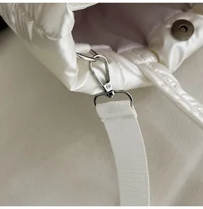 Détail du fermoir mousqueton argenté et du bouton magnétique sur le sac blanc matelassé