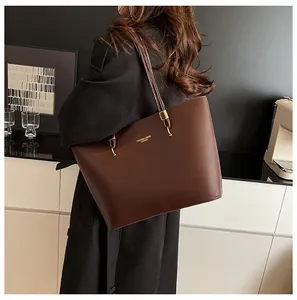 Detail view of smooth dark brown leather texture and golden embossed logo on tote bag