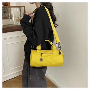 Detail of a bright yellow cylindrical sports bag with black zippers and adjustable strap