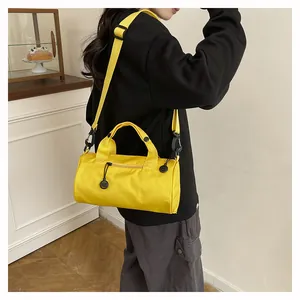 Detailed view of bright yellow cylindrical mini crossbody bag with adjustable black strap