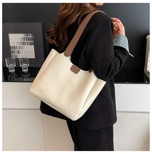 Detailed shot of large cream tote bag with brown straps and vertical stitching detail