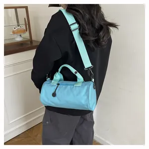 Detail of light blue cylindrical travel bag with sturdy handles and adjustable strap