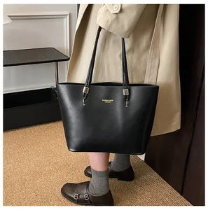 Detail of black leather tote bag featuring gold FASHION & BAGS lettering and slim strap