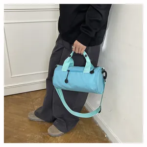 Close-up of lightweight light blue cylindrical travel bag shown being worn by a model