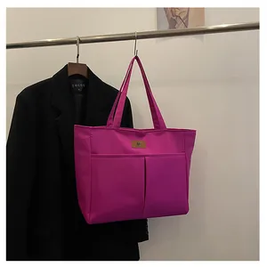 Detail van de roze nylon draagtas met twee voorzakken en bruin lederen logo-label erop