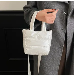 Gros plan d'un mini sac matelassé blanc en tissu brillant avec des crochets élégants