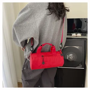 Close-up of the red cylindrical travel bag with top handles and adjustable shoulder strap