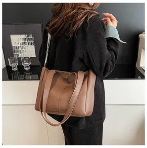 Detail view of brown tote bag featuring vertical stitching and minimalist slim shoulder straps
