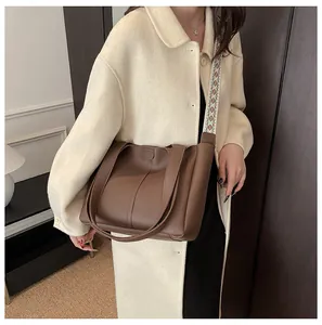 Detail of dark brown PU leather tote bag featuring ethnic style woven shoulder strap