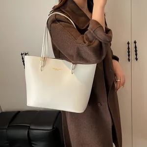 Off-white faux leather tote bag with gold lettering shown on a model in wool coat