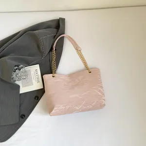Borsa tote rosa a pieghe con catena dorata su un elegante blazer grigio in posa flat lay