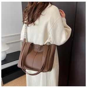 Brown leather tote bag with stylish patterned woven shoulder strap on model
