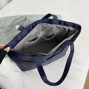 Donkerblauwe nylon tote bag met ruime binnenzakken en een stevige ritssluiting