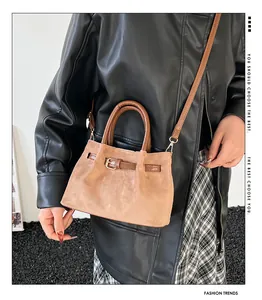 Close-up of brown faux suede handbag with contrasting dark brown leather straps and metal buckle