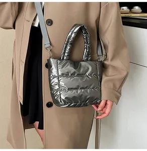 Sac bandoulière matelassé argenté porté par un mannequin avec un trench-coat élégant