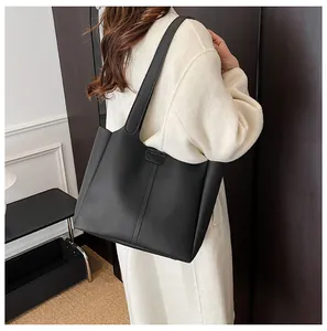 Classic black leather tote bag with vertical stitching shown on model in indoor setting
