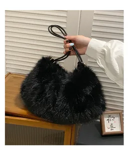 Detailansicht einer schwarzen Kunstpelz-Tasche mit Lederriemen auf einem Holzschrank