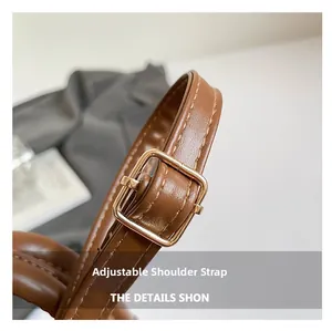 Close-up of adjustable brown leather shoulder strap with gold-tone metal buckle and stitching