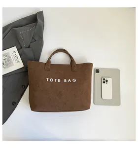 Detail view of a large brown suede tote bag with white lettering for daily commute
