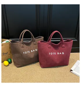Detail of dark brown and wine red tote bags with large white printed text in a home setting