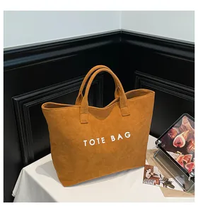 Macro detail of brown suede tote bag featuring white letter print and premium texture