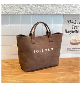Detailed close-up of dark brown tote bag with white lettering on a textured surface