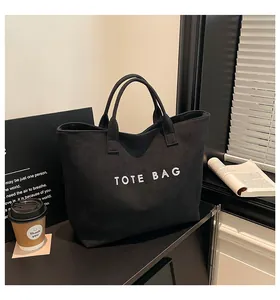 Close-up of minimalist black tote bag with white text on durable canvas fabric