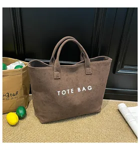 Detail view of large dark brown suede tote bag with white TOTE BAG lettering print