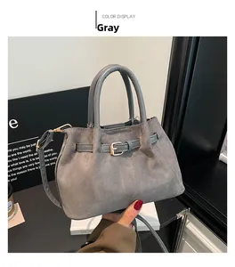 Detail of grey suede tote bag featuring metallic gold buckle and textured handle